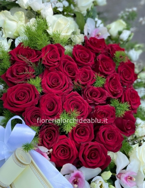 Composizione a forma di cuore con rose di colori assortiti.